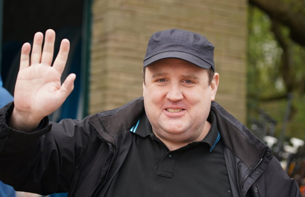 Peter Kay waves to photographers 